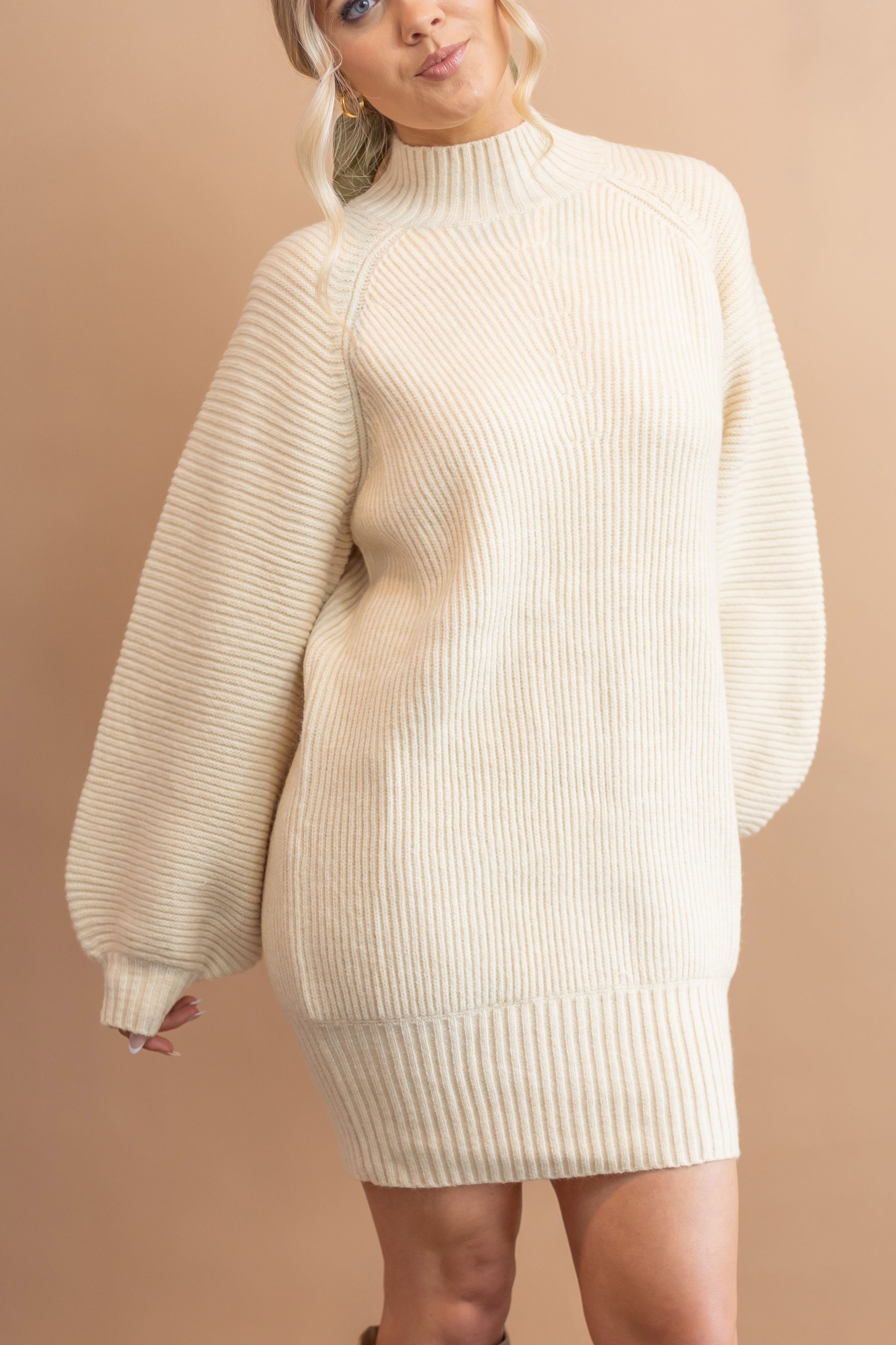 woman's cream sweater dress, billow sleeves, mid thigh, high neck